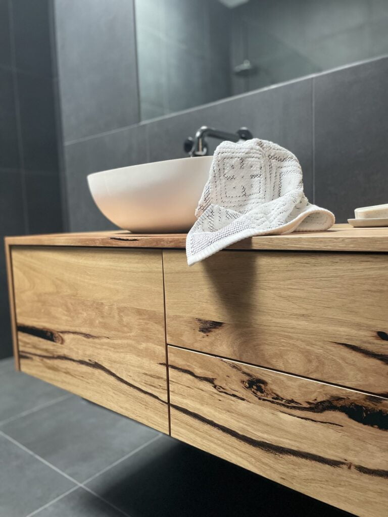 Elegant wooden vanity with a vessel sink and modern faucet in a stylish bathroom, installed by Bay Plumbing and Drainage in Geelong.