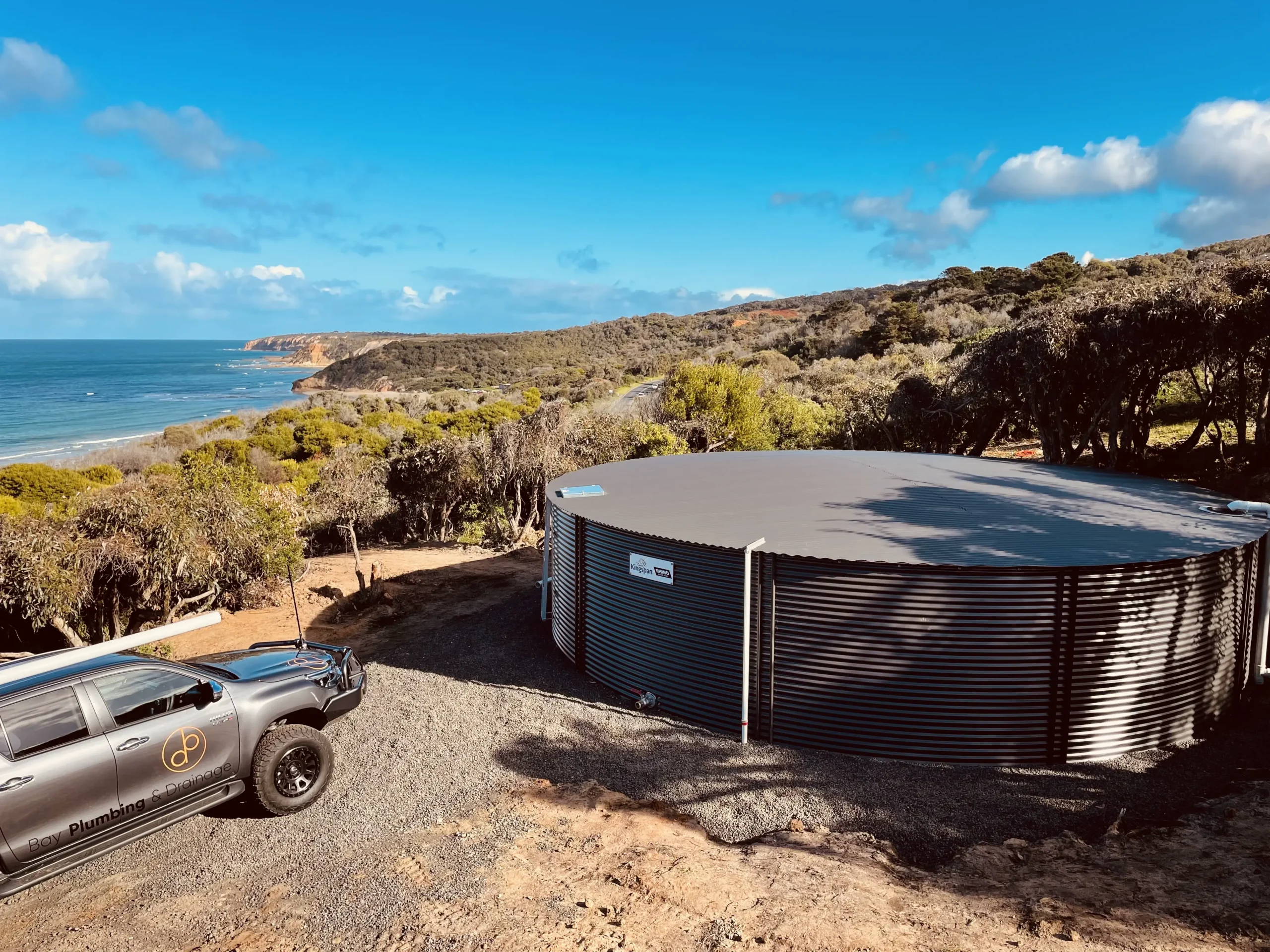 Large corrugated steel water tank installed on a coastal property for rainwater harvesting.