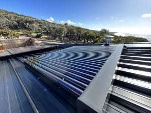 A solar water heater installation from Bay Plumbing and Drainage on a rooftop in Anglesea, with a scenic view of the ocean in the background.