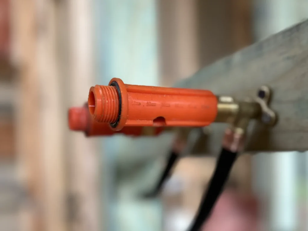 lexible orange gas hose connected to appliance, demonstrating safe gas installation practices.