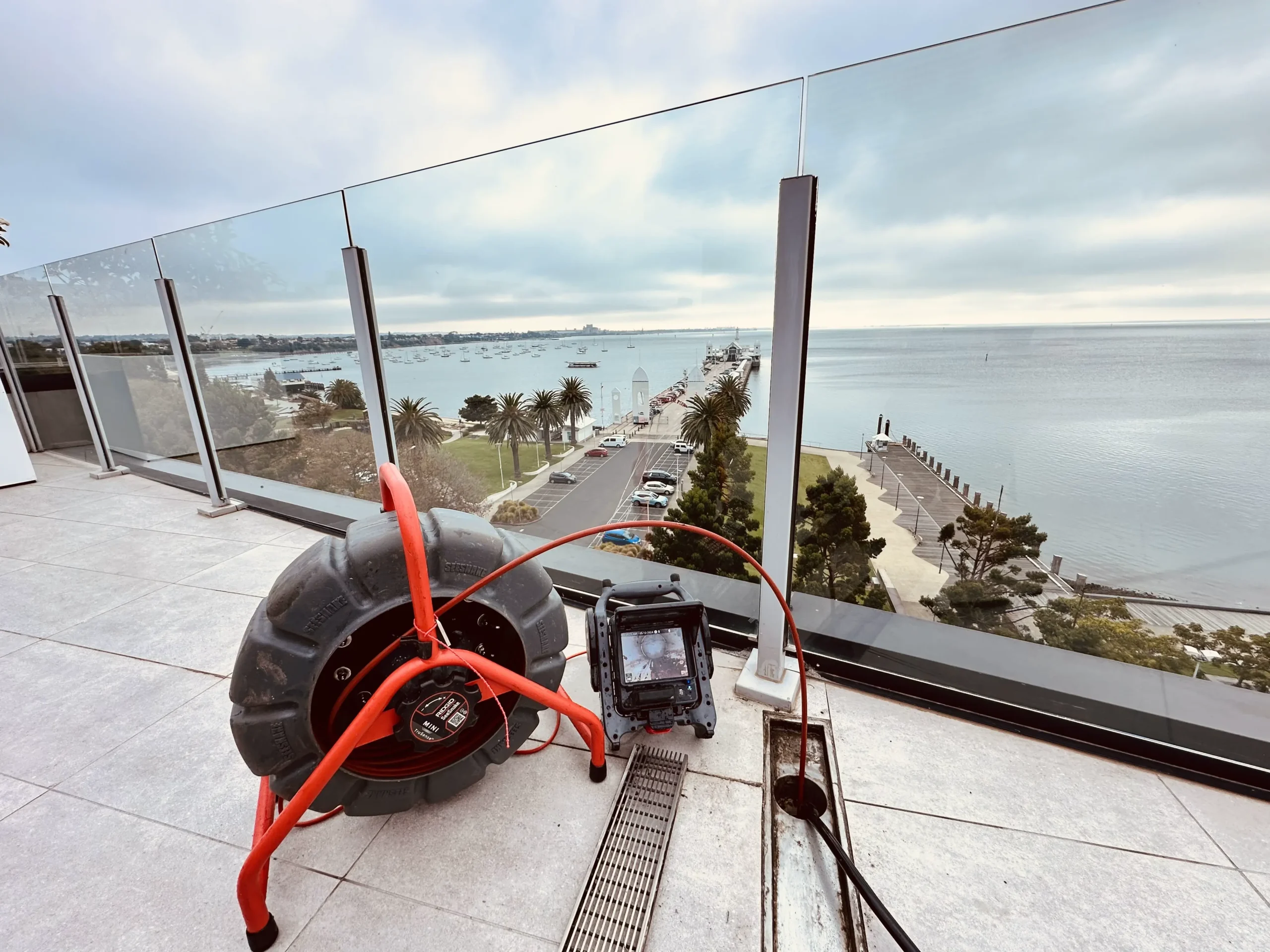 Drain inspection equipment set up on a rooftop to check blocked drains in a strata complex.