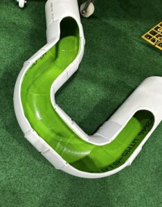 Cross-section of a 100mm drainage trap cut in half, showing green cloth drain relining securely attached to PVC pipe, demonstrating how relining bonds to the internal pipe surface during installation