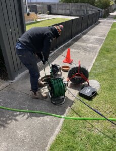 Bay Plumbing & Drainage Plumber cleaning and CCTV drainage inspecting a sewer pit in the street.