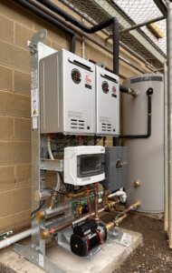 Commercial hot water system frame and Gas boosters with plumbing connections to a building exposed