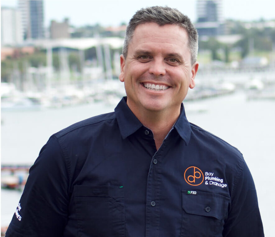 LF - BPD Promo shot Owner of Bay Plumbing & Drainage smiling in branded workwear near the Geelong waterfront, representing professional and local plumbing services.