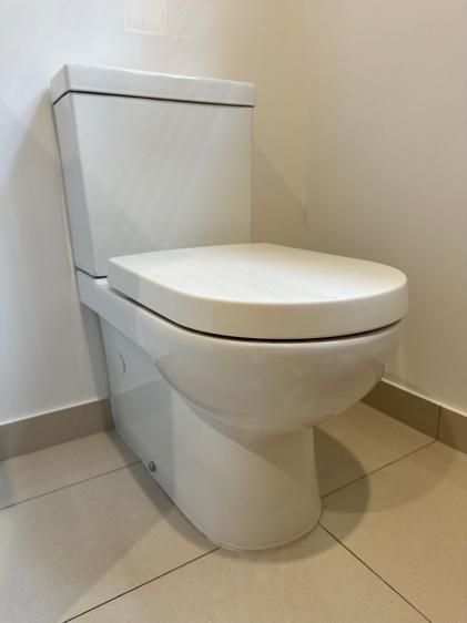 Close up of a white toilet with the lid closed in a bathroom.