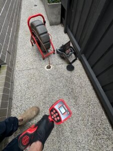 Plumber with inspection equipment and drainage camera inspecting a drain under concrete