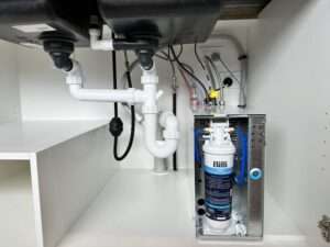 Under-sink installation in Geelong featuring intricate plumbing and a Billi water filtration system, meticulously installed by Bay Plumbing and Drainage.